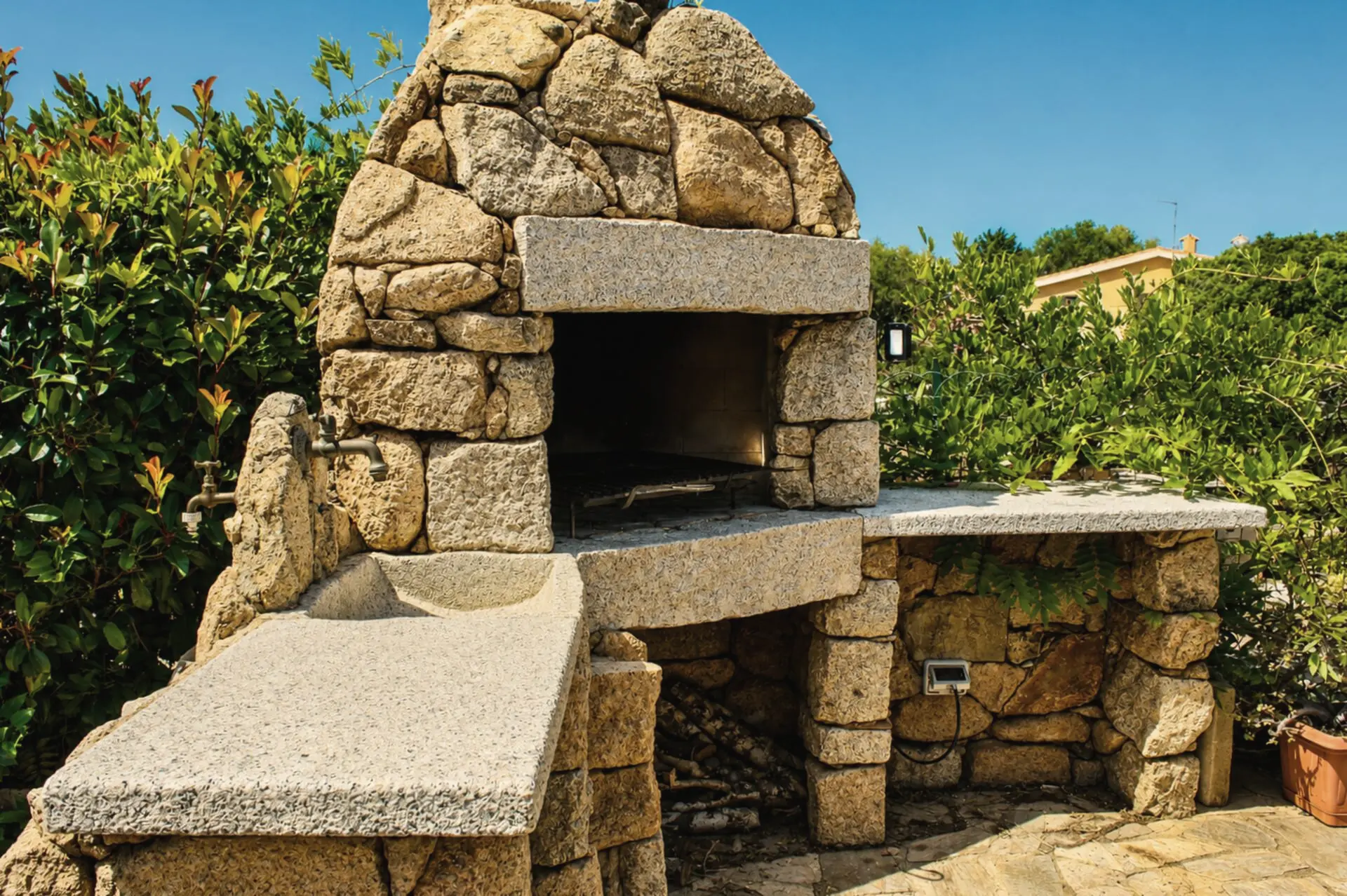 Il forno di pietra in granito, con il piano di lavoro e le piante intorno