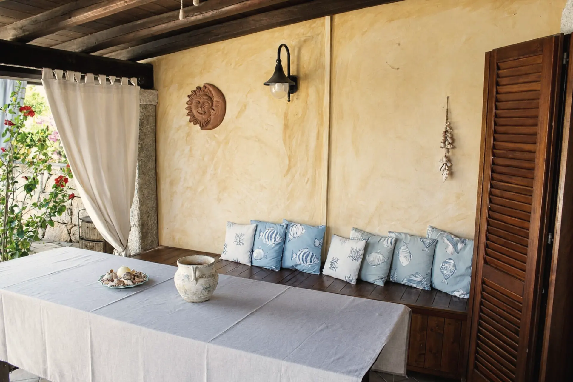 La veranda di Villa Rosa 4 con il tavolo apparecchiato e la panca di cuscini